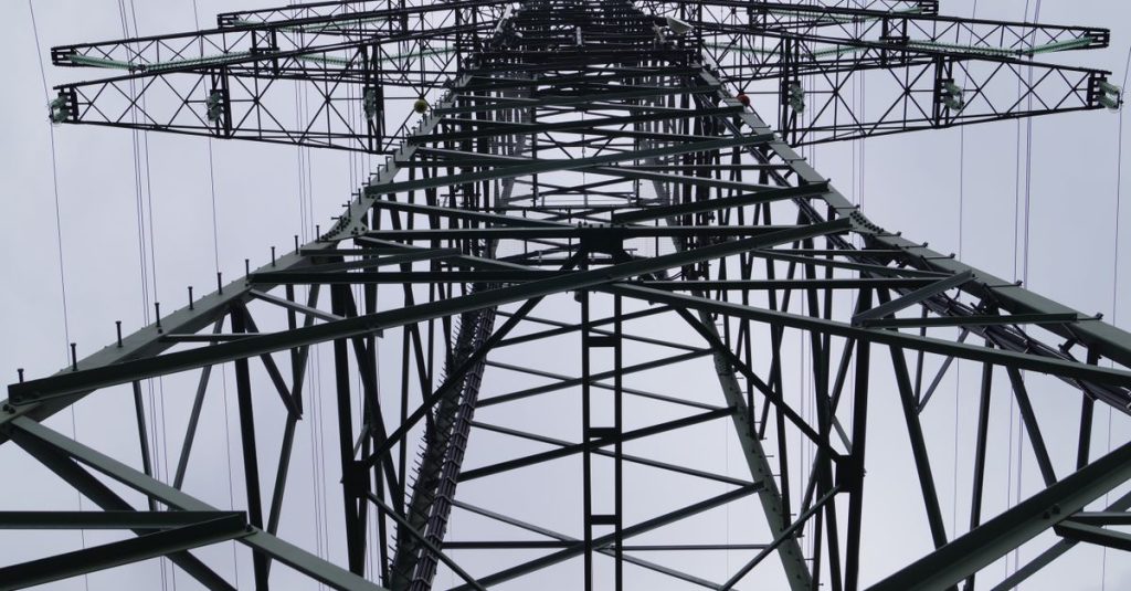 Close-up low angle view of a metal electricity pylon against a cloudy sky.