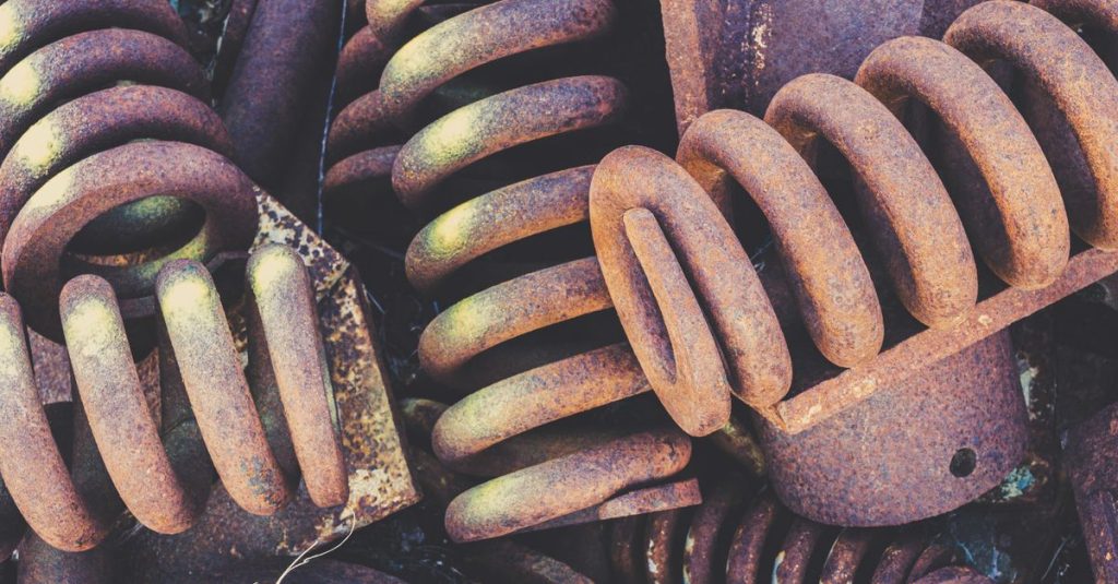 Detailed view of weathered and rusted metal springs in a scrapyard setting.