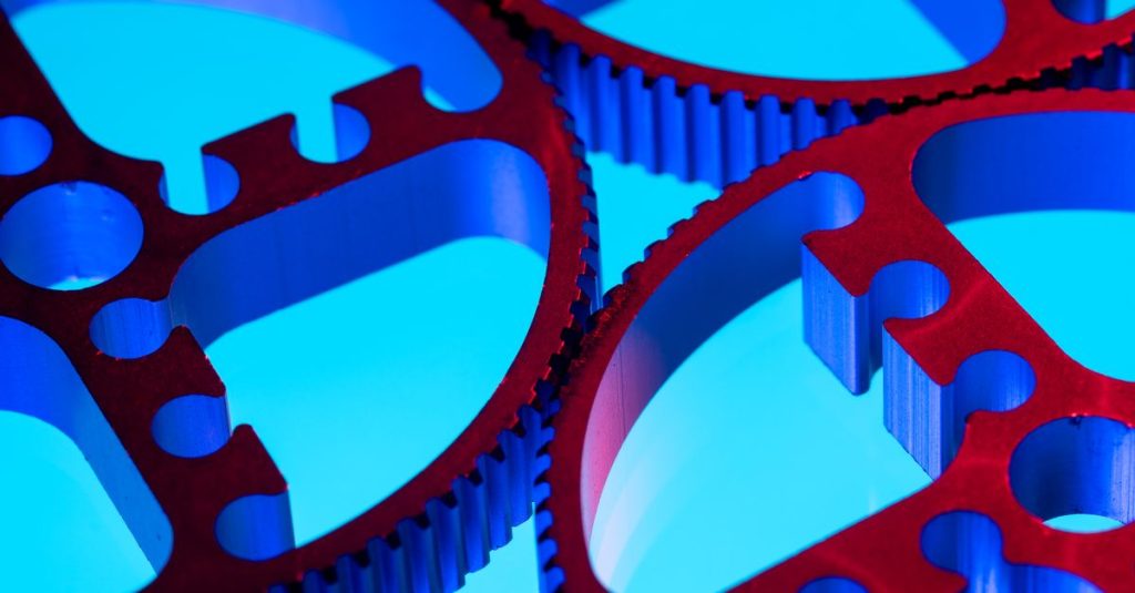 Macro shot of vibrant red gears on a blue background illustrating industrial precision and technology.