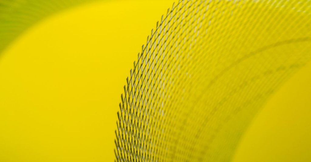 Close-up of abstract yellow curved wire mesh pattern with vibrant colors creating a modern artistic look.