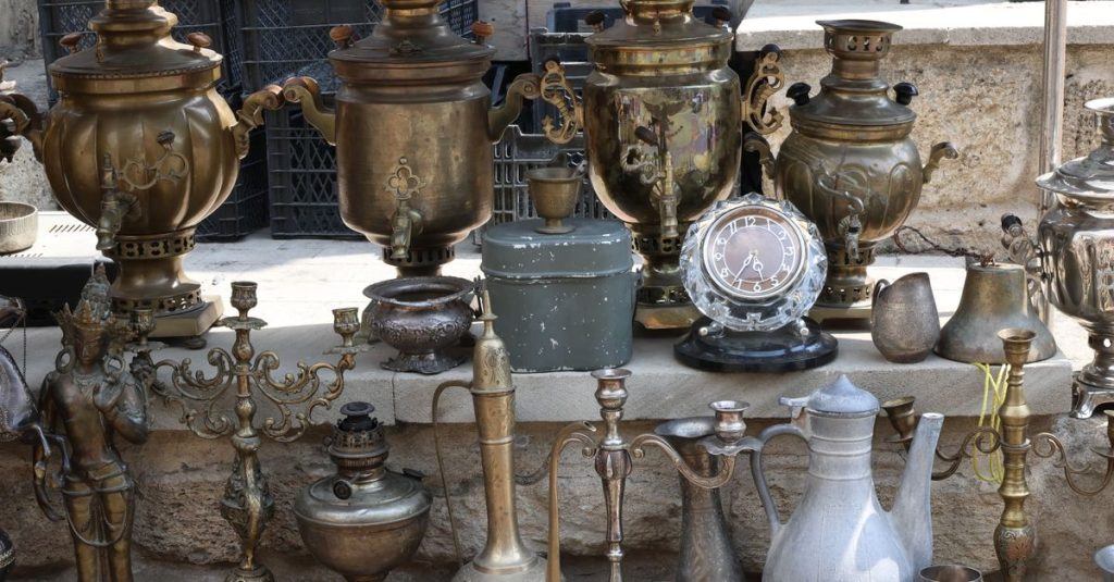 Collection of vintage brass samovars and antiques in an outdoor market setting.