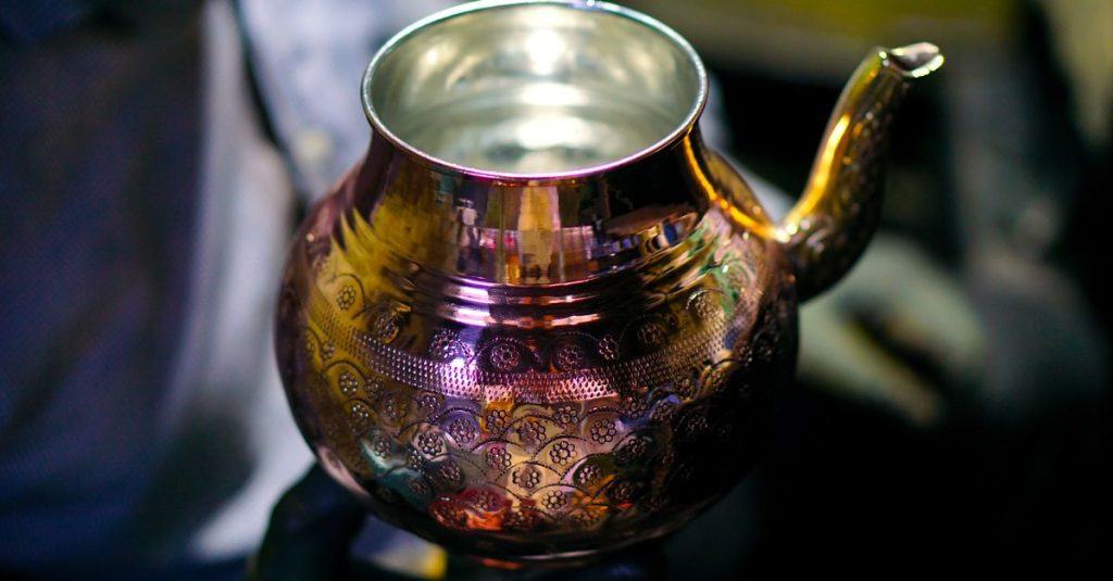 Handcrafted copper teapot with intricate patterns held by artisan in Gaziantep, Türkiye.