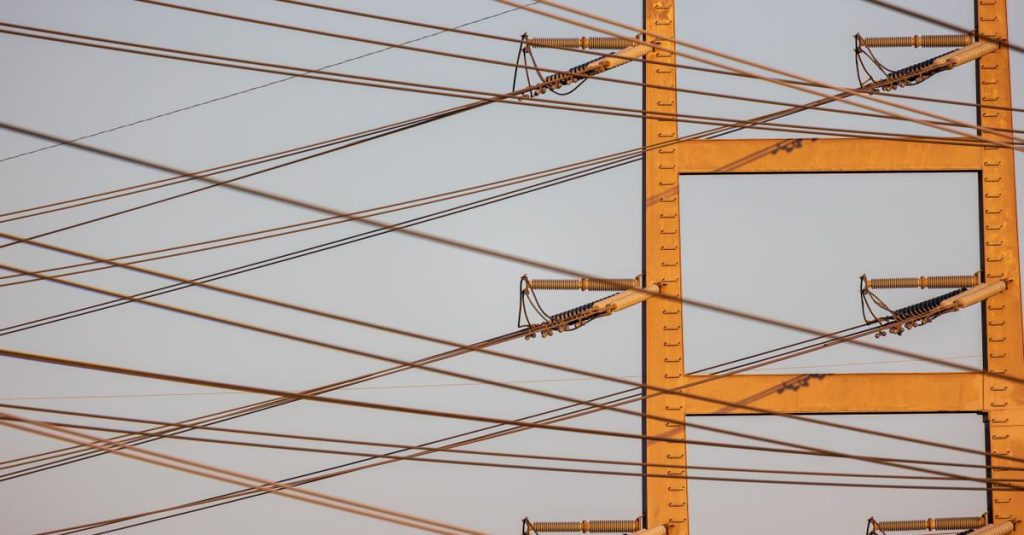 High voltage power lines with sunset sky background, illustrating energy distribution.