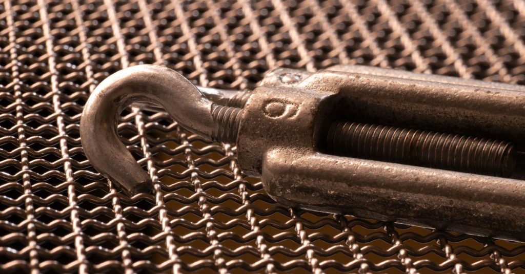 Detailed image of a metal hook on intricate woven mesh, showcasing industrial textures.