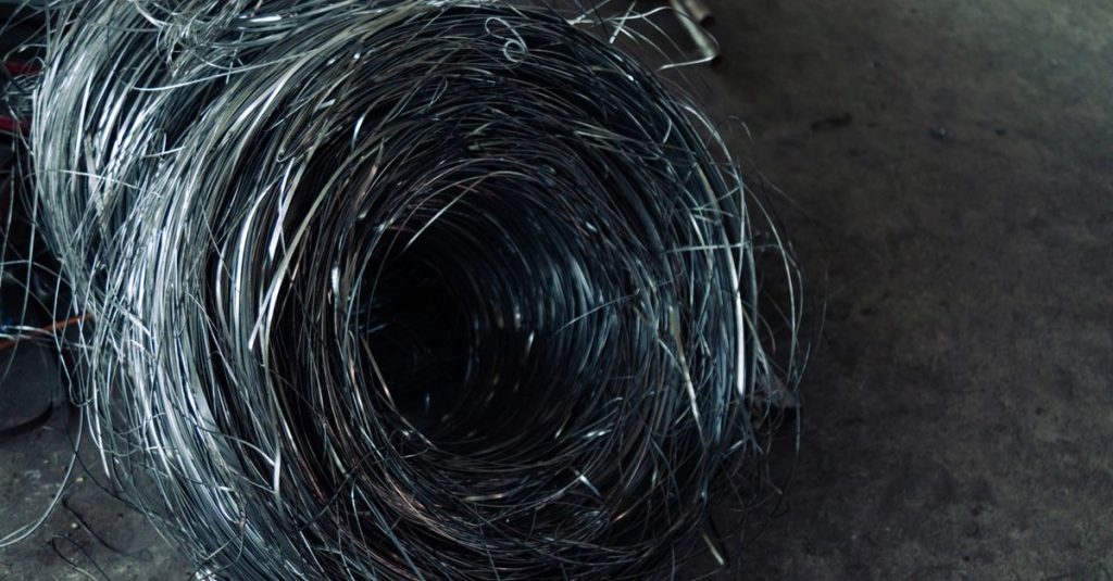 A roll of coiled metal wire in a factory setting, highlighting industrial textures.
