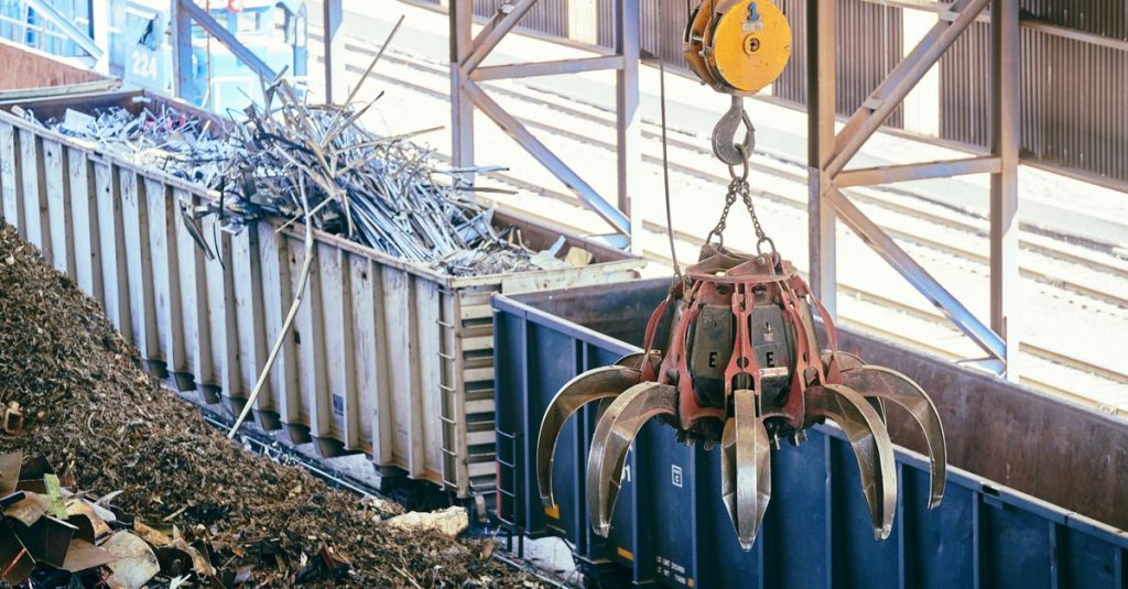 Overhead crane sorting scrap metal in an industrial recycling facility.