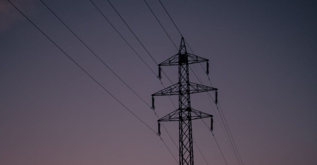 Silhouette of an electric tower against a twilight sky, representing industrial infrastructure.