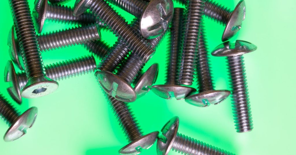 High-impact image of metallic screws scattered on a vibrant green surface.