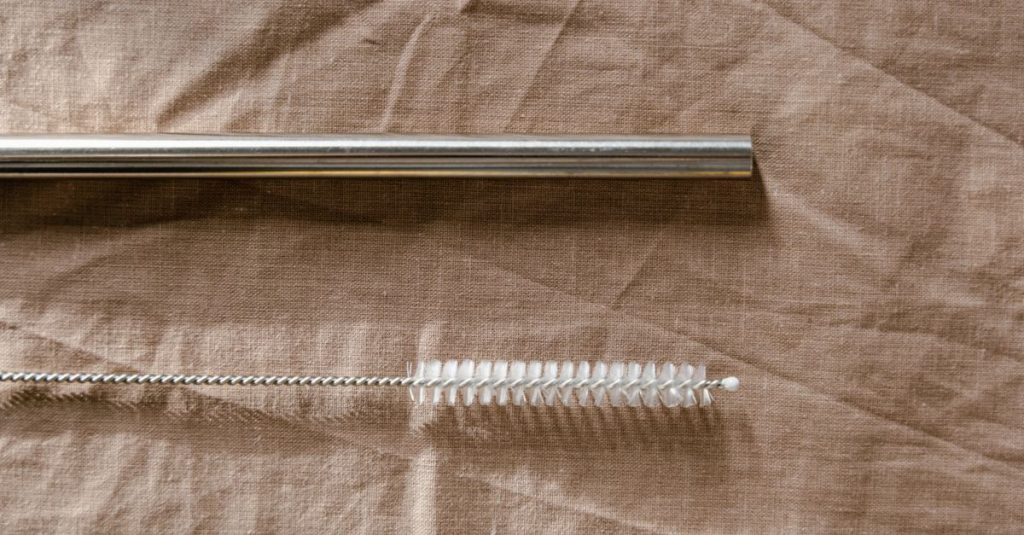 Şahinbey Hurdacı Eco-friendly metal straw and cleaning brush on a fabric background.