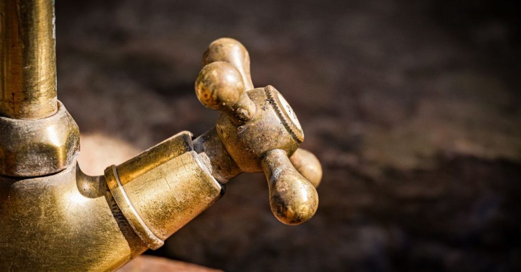 Detailed shot of an old brass faucet handle with rustic texture.