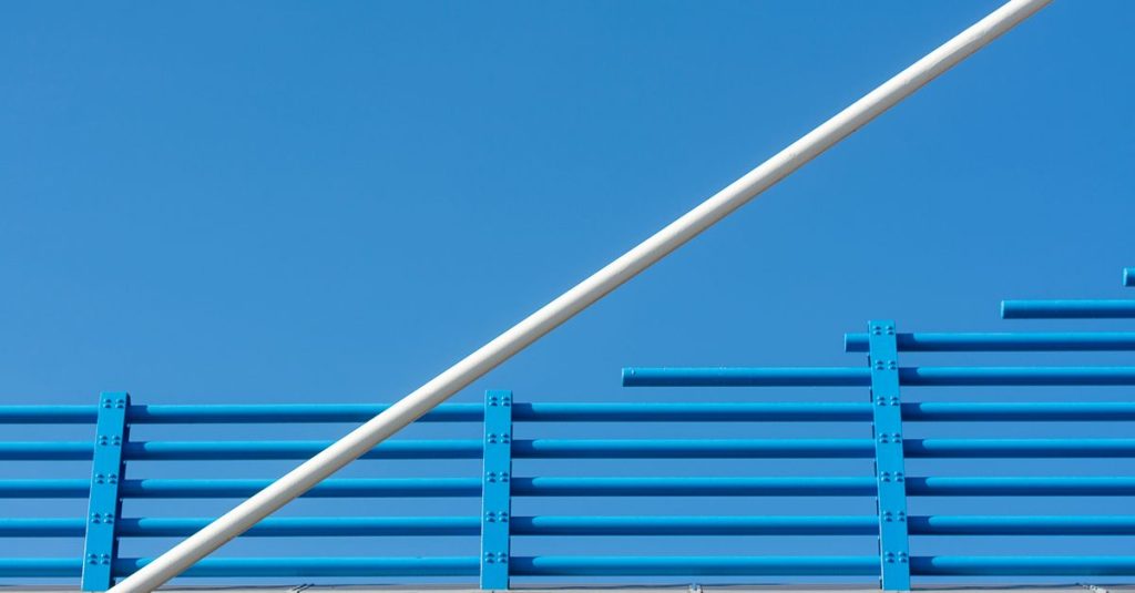 Minimalist architectural structure featuring blue and red lines against a clear blue sky.