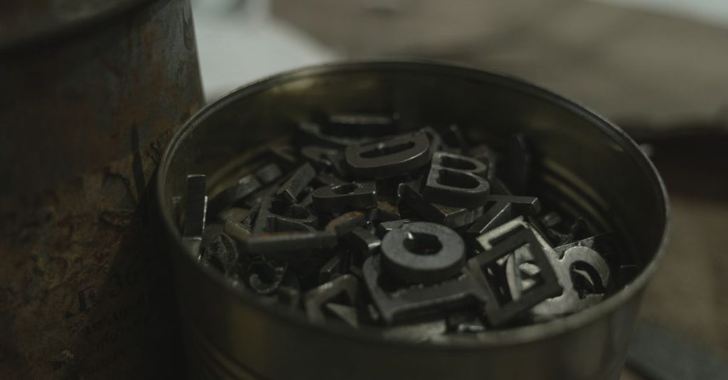 Yazıhan Hurdacı A bucket of metal letter stamps in an indoor industrial environment.