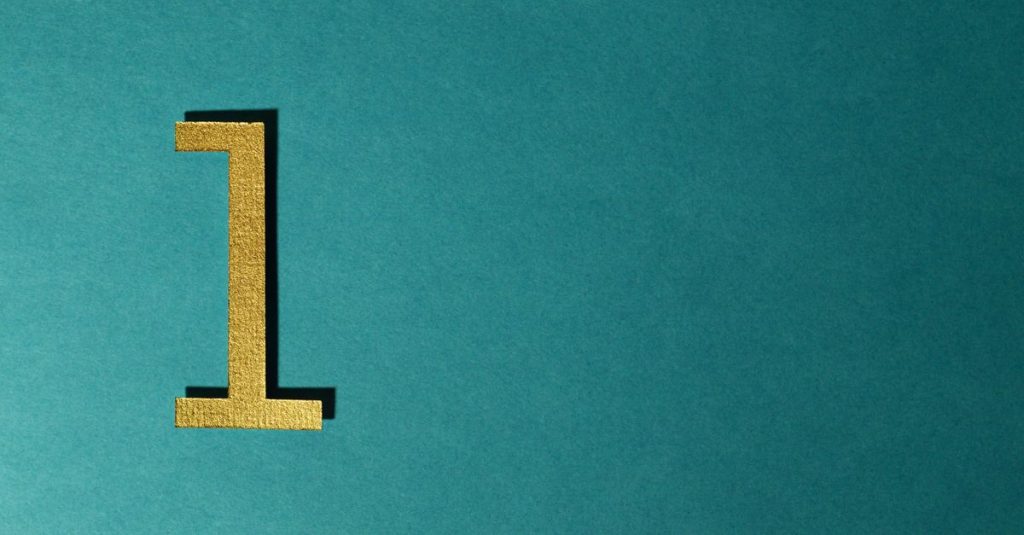 A gold number one on a teal background with ample copy space.
